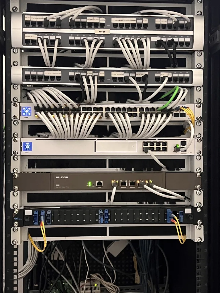 UniFi network rack with two 48-port patch panels and neatly dressed white cords