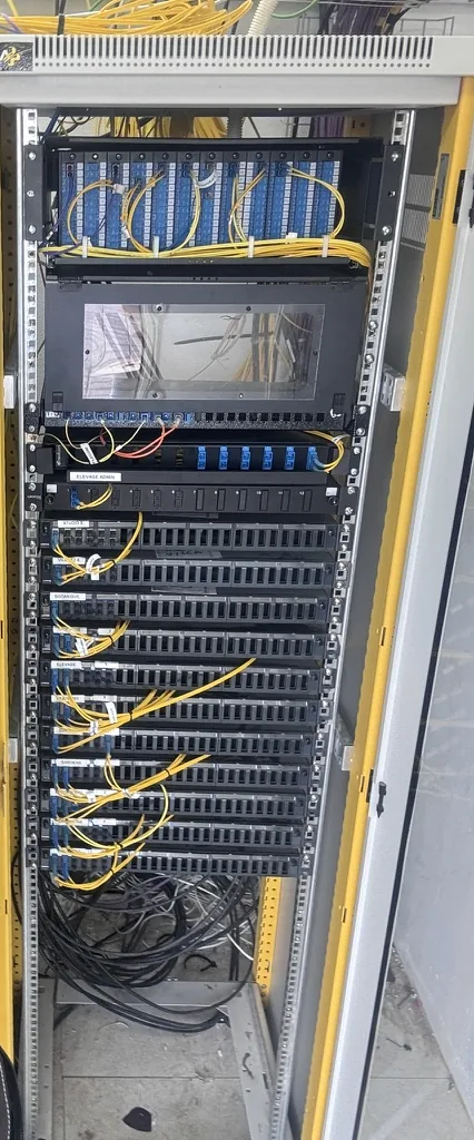 Fibre distribution frame. Trays labelled by building, dressed patch cords, cables entering from below.
